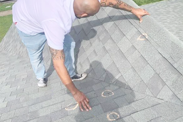 roof inspector inspecting exposed nail in roof shingles